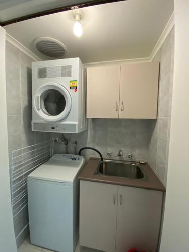 a small kitchen with a sink and a microwave at West End Apartments in Fremantle