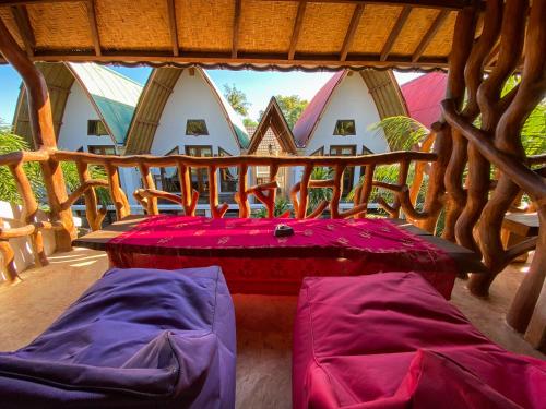 a room with a bed and two chairs on a porch at Sayang Mama Inn in Gili Air