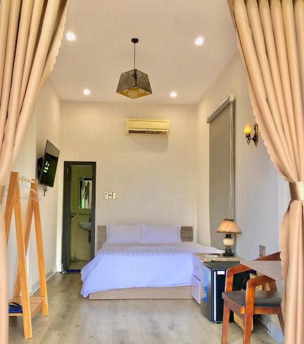 a bedroom with a white bed and a table and a desk at The Cau Garden House in Ấp Long Hồ Hạ