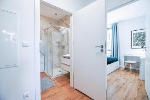 La salle de bains blanche est pourvue d'une douche et d'un lavabo. dans l'établissement CITYSTAY Garden Gates Apartment, à Gdańsk