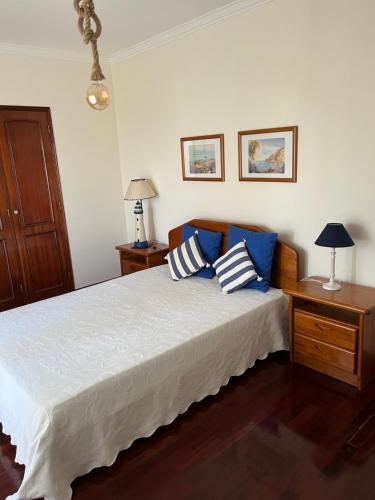 um quarto com uma cama com almofadas azuis e brancas em COZY APARTMENT ERICEIRA WITH SEA VIEW na Ericeira