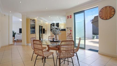 a dining room with a table and chairs and a clock at Market Street Penthouse in Merimbula