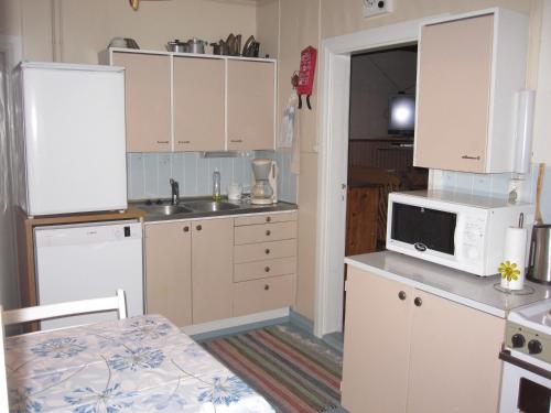cocina con armarios blancos y microondas en Farmhouse Tervamäki, en Tervajärvi