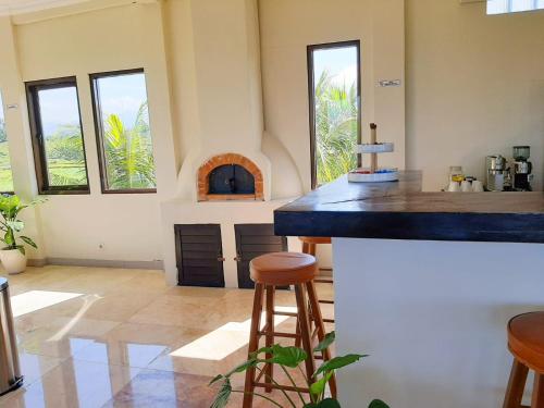 a kitchen with a counter with stools and a fireplace at Medewi Manor in Airsatang