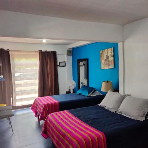 een slaapkamer met 2 bedden en een blauwe muur bij Casa LUNA in Misiones de La Paz