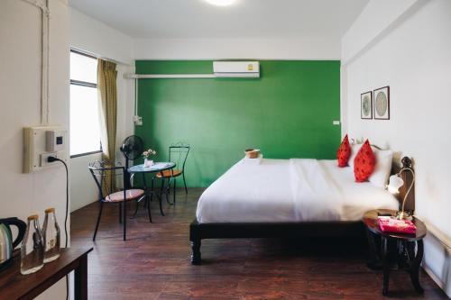 een groene kamer met een bed en een groene muur bij Sleeper House in Trang