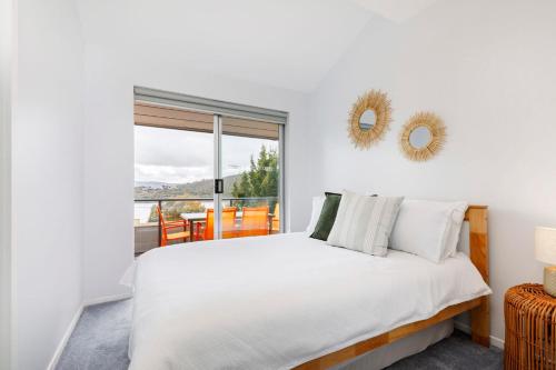 a white bedroom with a bed and a window at Kooringa 4 in Jindabyne