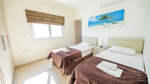 a bedroom with two beds and a window at Protaras Holiday Villa 045 in Protaras