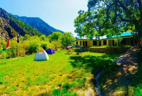 a field with a tent and a building at Chitral Inn Resort (Kalash Valley) in Chitral