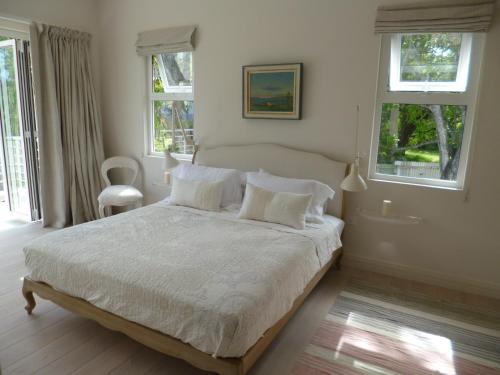 a bedroom with a bed with white sheets and windows at Villa Mimi in Beau Vallon