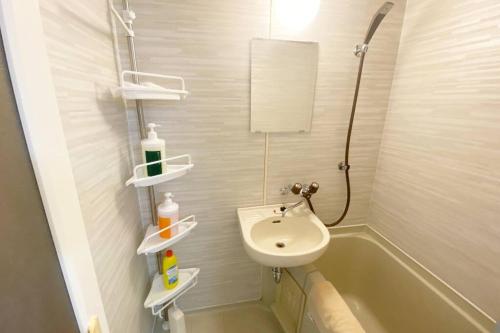 a bathroom with a sink and a bath tub at ラ・ポート空港前101 in Shime