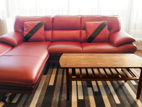 a red leather couch in a living room with a coffee table at Hotel Abest Grande Okayama in Okayama
