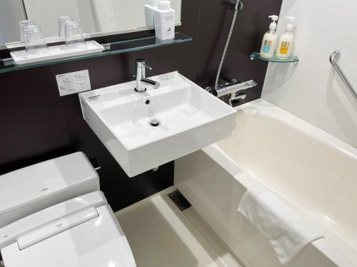 a bathroom with a white sink and a toilet at Hotel Abest Grande Okayama in Okayama