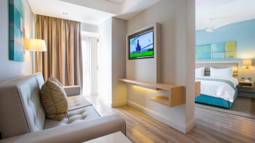 a hotel room with a bed and a tv at Holiday Inn Mauritius Mon Trésor by IHG in Blue Bay