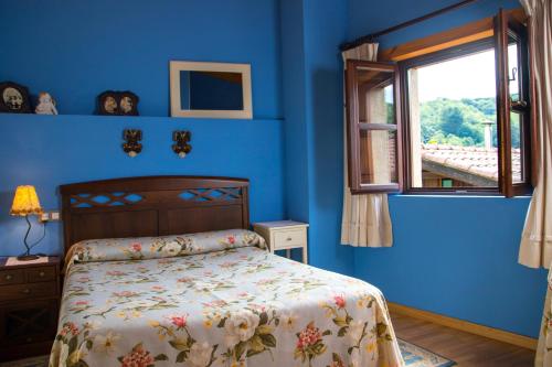 a blue bedroom with a bed and a window at Casa Canela in Colladas