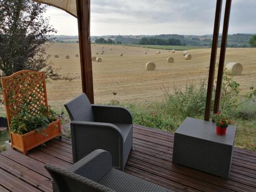a porch with chairs and a field with hay bales at La petite maison dans la prairie 