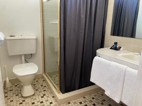 a bathroom with a shower and a toilet and a sink at Ben Hall Motor Inn in Forbes