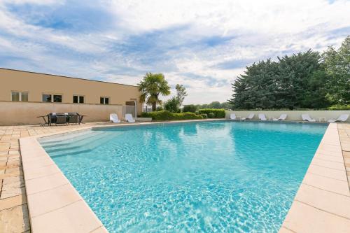 a large swimming pool with chairs and a table at Kyriad Prestige Beaune le Panorama in Beaune
