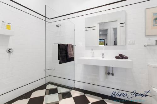 Baño blanco con lavabo y espejo en Hideaway Nook by Wine Coast Holiday Rentals, en Willunga