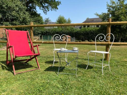 two chairs and a table in the grass at La petite ferme de Roumare in Roumare