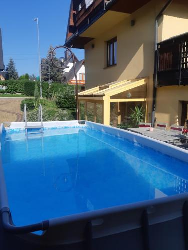 a large blue swimming pool in front of a house at Apartamenty i pokoje gościnne Nowita in Zakopane