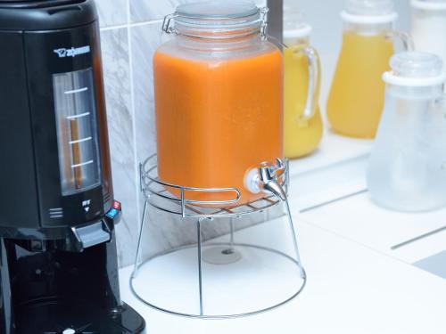 a jar of orange liquid in a stand next to a blender at Hotel Abest Grande Okayama in Okayama