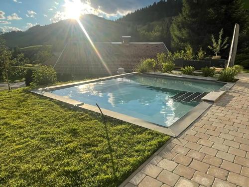 una piscina en un patio con el sol al fondo en Premium chalet in Wagrain with 2 saunas and pool, en Wagrain