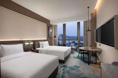 Habitación de hotel con 2 camas y TV de pantalla plana. en Wanda Jin Xiangjiang Dingzhou en Dingzhou