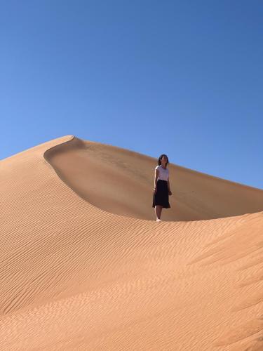 a woman standing on top of a sand dune at Luxury Desert Camp Oman in Al Wāşil
