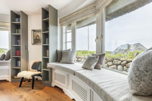 1 dormitorio con asiento junto a la ventana y vistas al océano en Ferienhaus Seehaus Sylt - Urlaubszauber in den Dünen mit fantastischem Meerblick, en Rantum