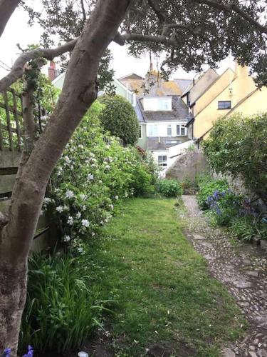 a garden with flowers and a tree and buildings at Fermaine, 50m from sea, garden, dogs, town centre in Lyme Regis
