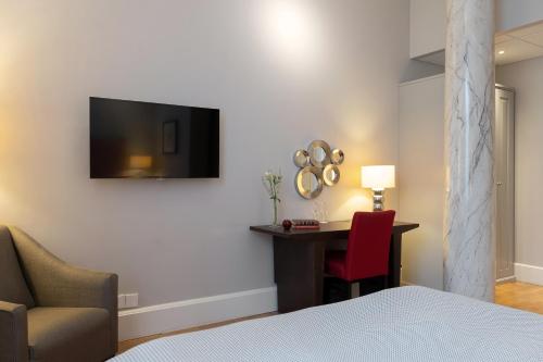 a hotel room with a desk and a tv on the wall at Elite Stadshotellet Västerås in Västerås