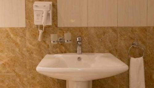 W łazience znajduje się biała umywalka i telefon. w obiekcie Mbale Courts View Hotel w mieście Mbale