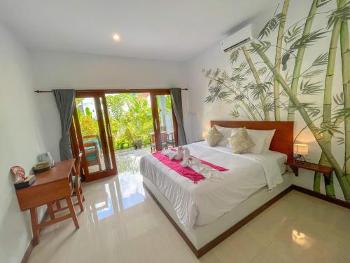 une chambre avec un lit, un bureau et une plante dans l'établissement Rumah Diyah, à Amed