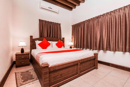 Capital O160 Lumbini Dream Garden Guest House LLC في دبي: غرفة نوم بسرير كبير ومخدات حمراء