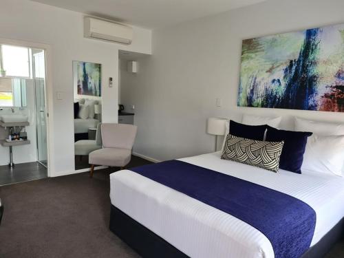 a bedroom with a large bed and a chair at The Avenue Inn in Naracoorte