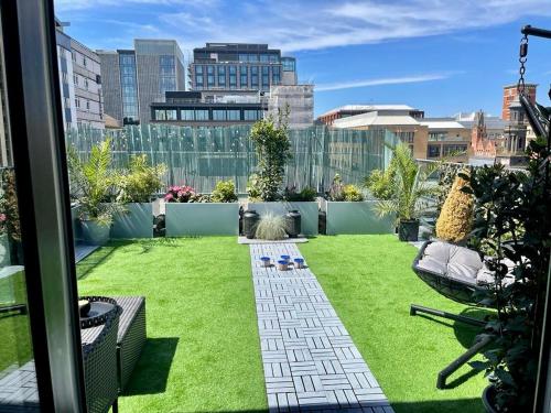 a garden with green grass and buildings in the background at Luxury 9ine PENTHOUSE WITH GARDEN & JACUZZI in Birmingham