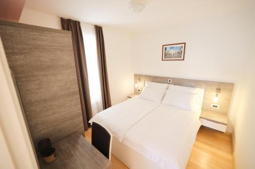 a bedroom with a white bed and a wooden floor at Dok Apartment in Petrcane