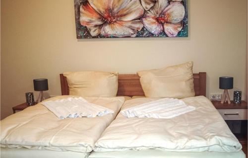 a bed with white sheets and a painting on the wall at Lovely Home In Gützkow With Kitchen in Gützkow