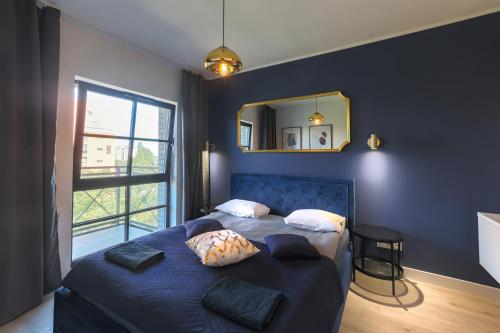 um quarto com uma cama azul com almofadas e um espelho em Apartament Centrum Gdańsk blisko Starego Miasta z widokiem na rzekę em Gdansk