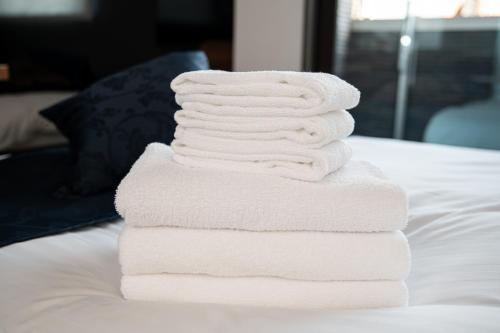a stack of white towels sitting on a bed at T・Kスクエア鹿児島中央 in Kagoshima