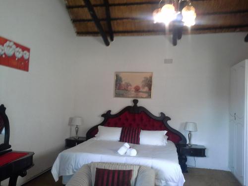 a bedroom with a white bed with a red headboard at Naleli Guest House in Selomas