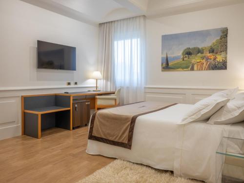 a bedroom with a bed and a desk and a television at Mirabella Hotel in Mirabella Eclano