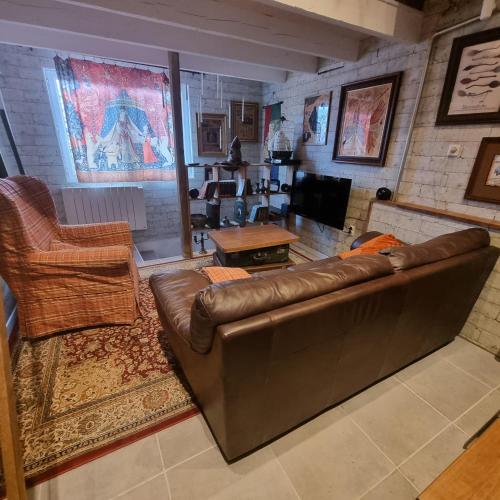 a living room with a brown leather couch and chairs at La cabane des sorciers in Liévin