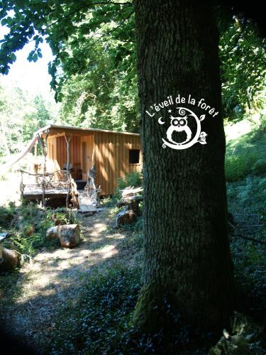 a sign on a tree in front of a cabin at Gîte nature Au pied des hêtres in Vitrac-sur-Montane