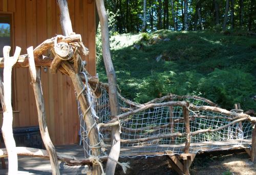 a wooden bench made out of branches next to a cabin at Gîte nature Au pied des hêtres in Vitrac-sur-Montane