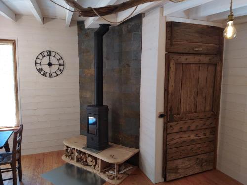 a stove in a room with a door and a clock at Gîte nature Au pied des hêtres in Vitrac-sur-Montane