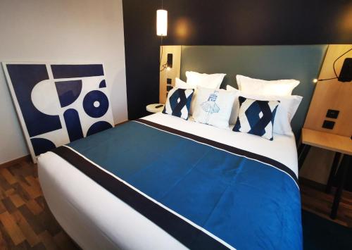 a bedroom with a blue and white bed with pillows at Residhome Asnieres in Asnières-sur-Seine