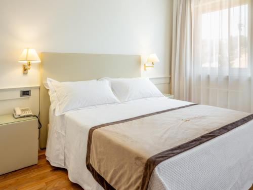 a bedroom with a large white bed and a phone at Mirabella Hotel in Mirabella Eclano