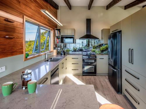 a kitchen with white counters and a black refrigerator at Roydons - Kaiteriteri Upstairs Holiday Unit in Kaiteriteri